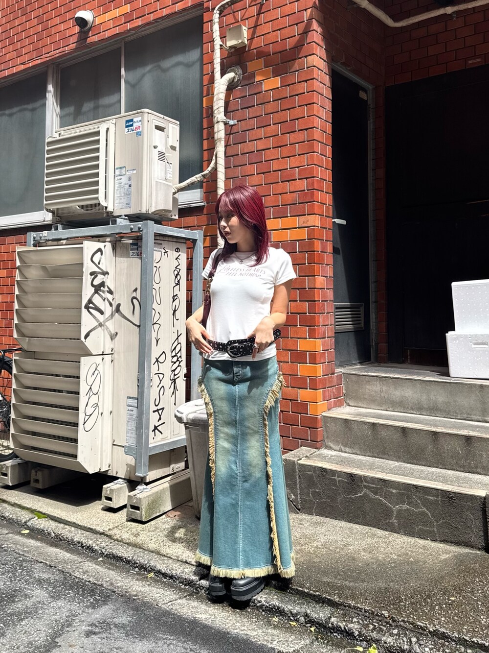 ブルー系のデニムスカート、ブラック系のブーツ、レッド系のハンドバッグを着用したレディースの夏コーディネートの2枚目の写真