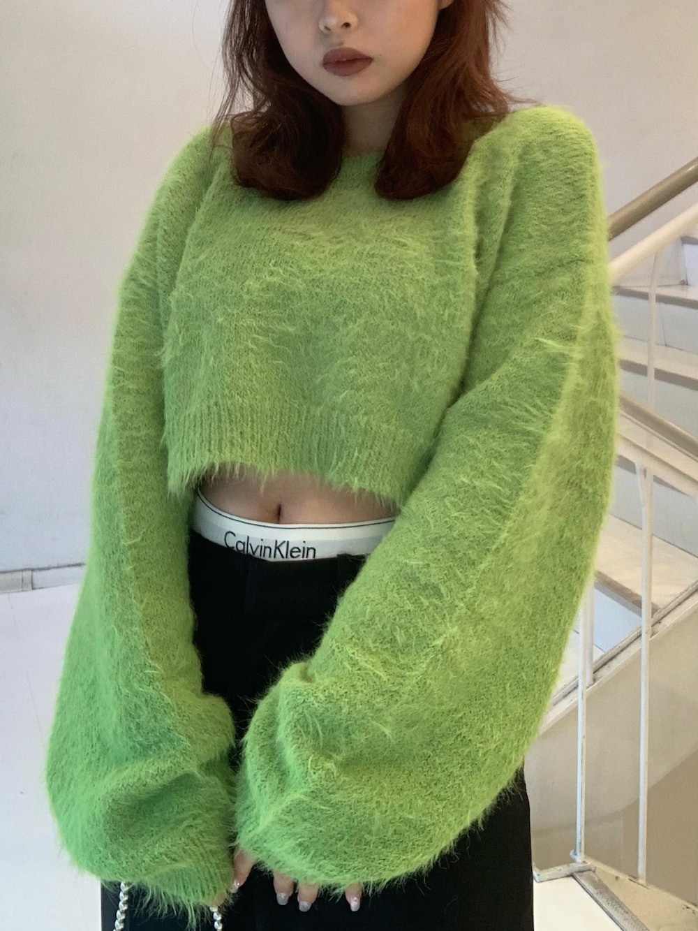 グリーン系のニット/セーター、ブラック系のその他パンツ、ブラック系のスリッポンを着用したレディースの冬コーディネートの4枚目の写真
