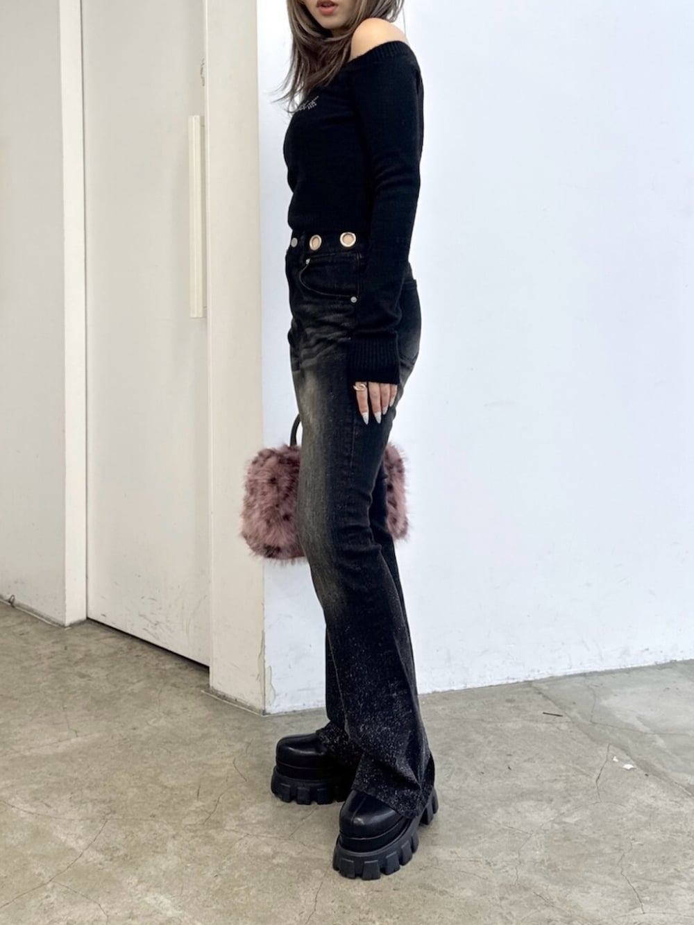 ブラック系のニット/セーター、ブラック系のデニムパンツ、ピンク系のボストンバッグを着用したレディースの夏コーディネートの2枚目の写真