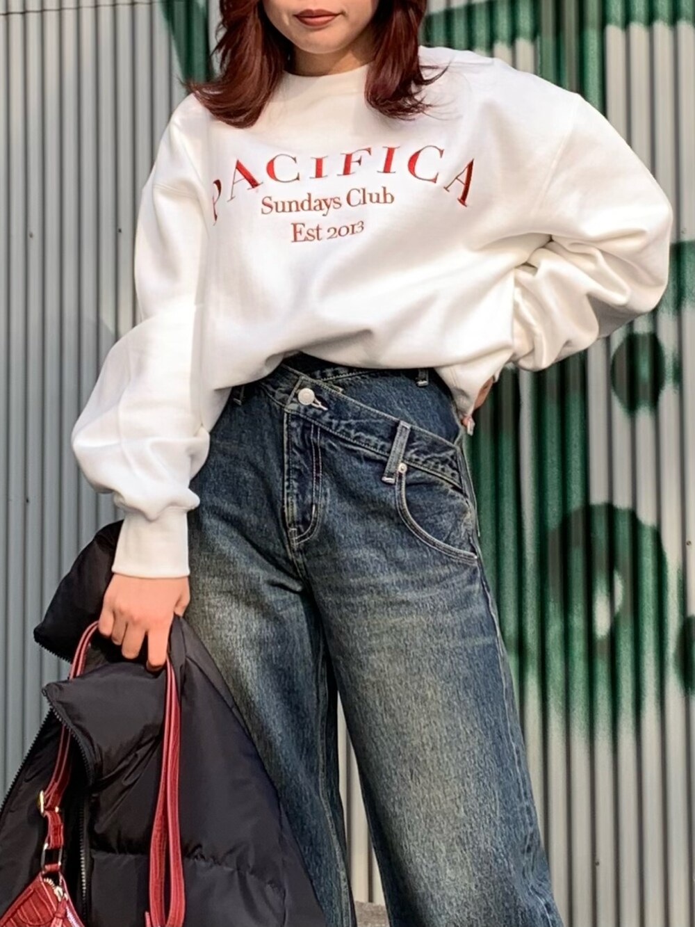 ブルー系のデニムパンツ、レッド系のショルダーバッグ、ブラック系のダウンジャケット/コートを着用したレディースの冬コーディネートの3枚目の写真