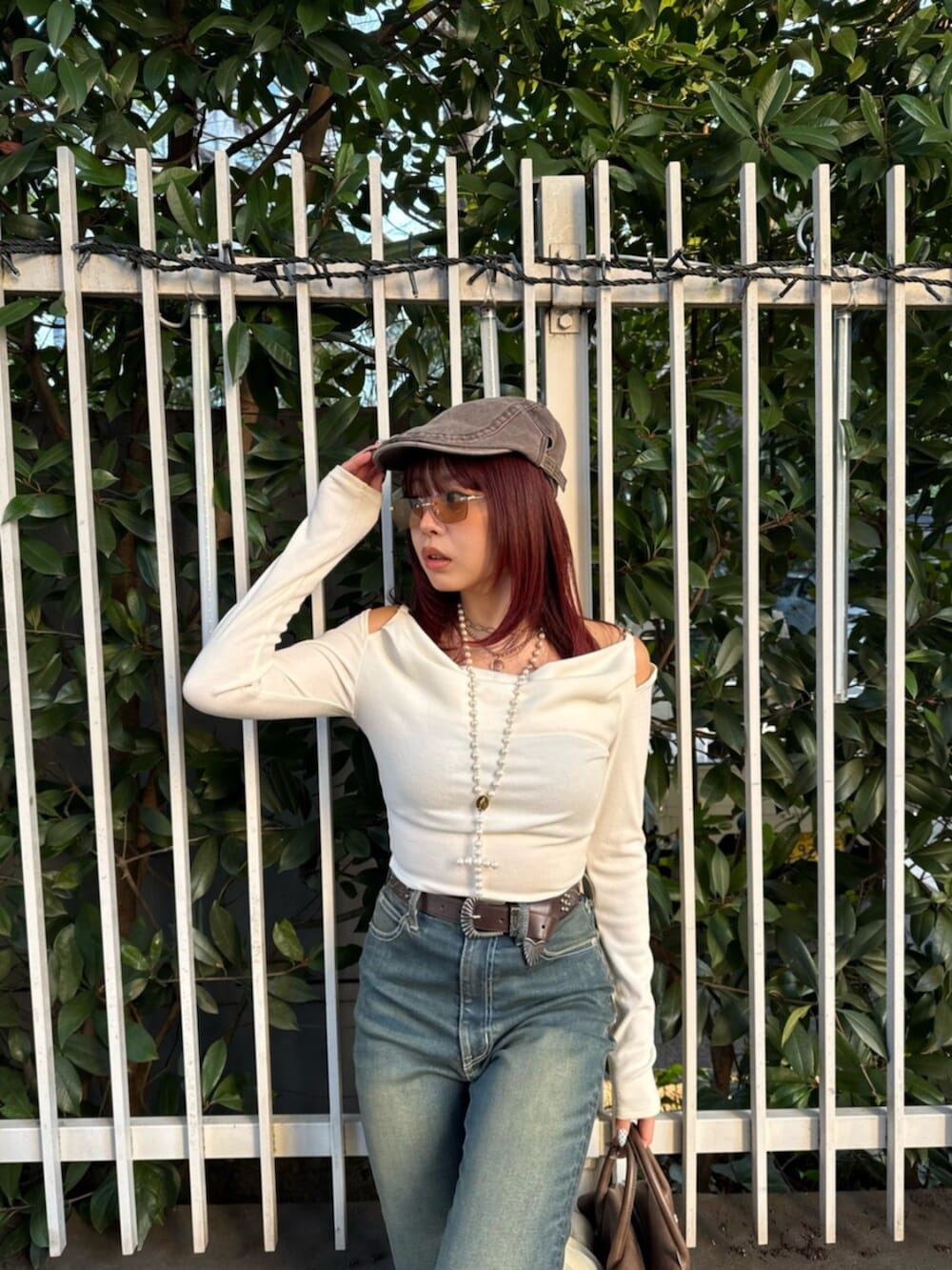 ブラウン系のボストンバッグ、ホワイト系のブーツ、ブルー系のデニムパンツを着用したレディースの春コーディネートの4枚目の写真