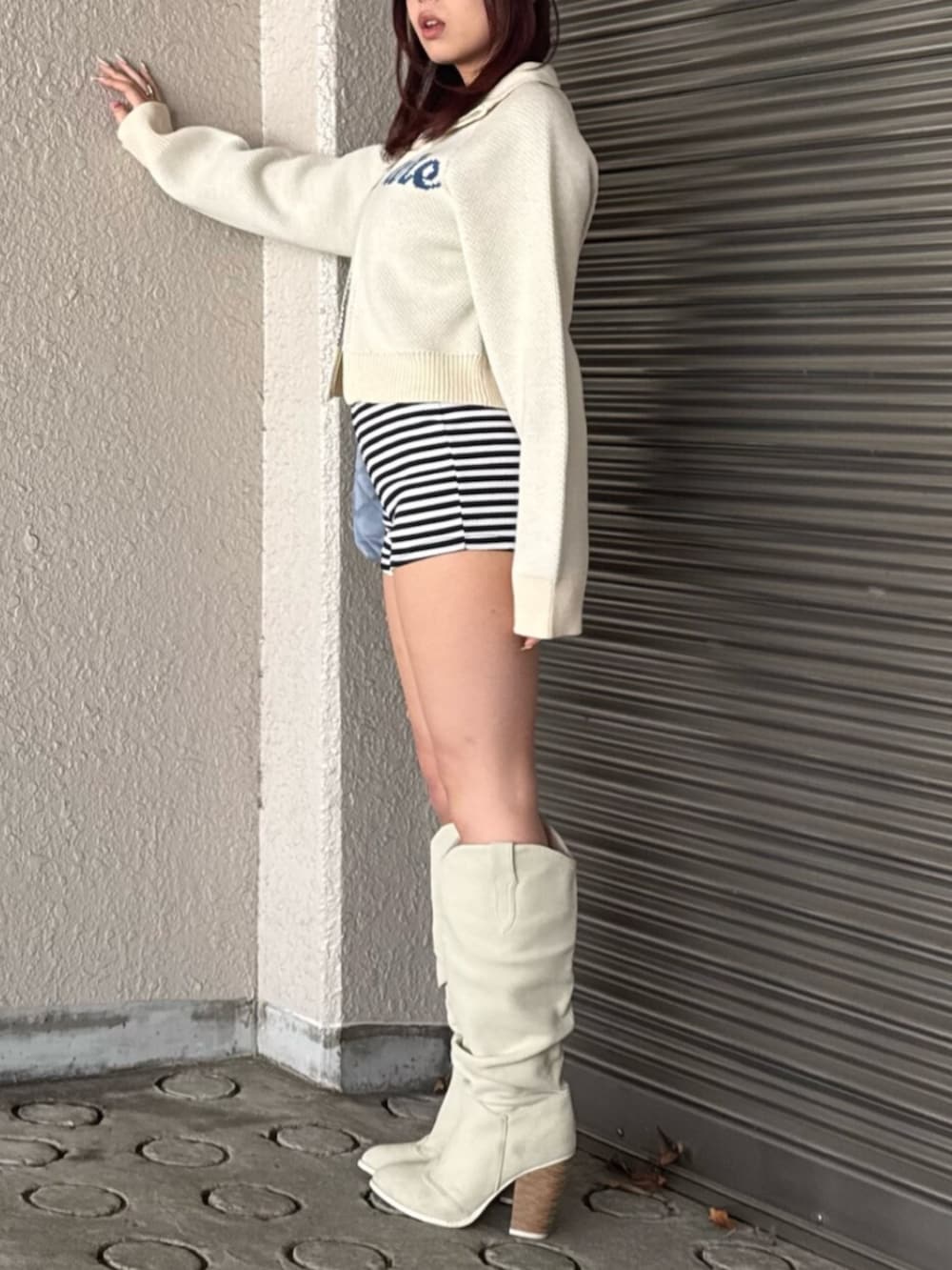 ホワイト系のニット/セーター、ホワイト系のブーツを着用したレディースの冬コーディネートの2枚目の写真