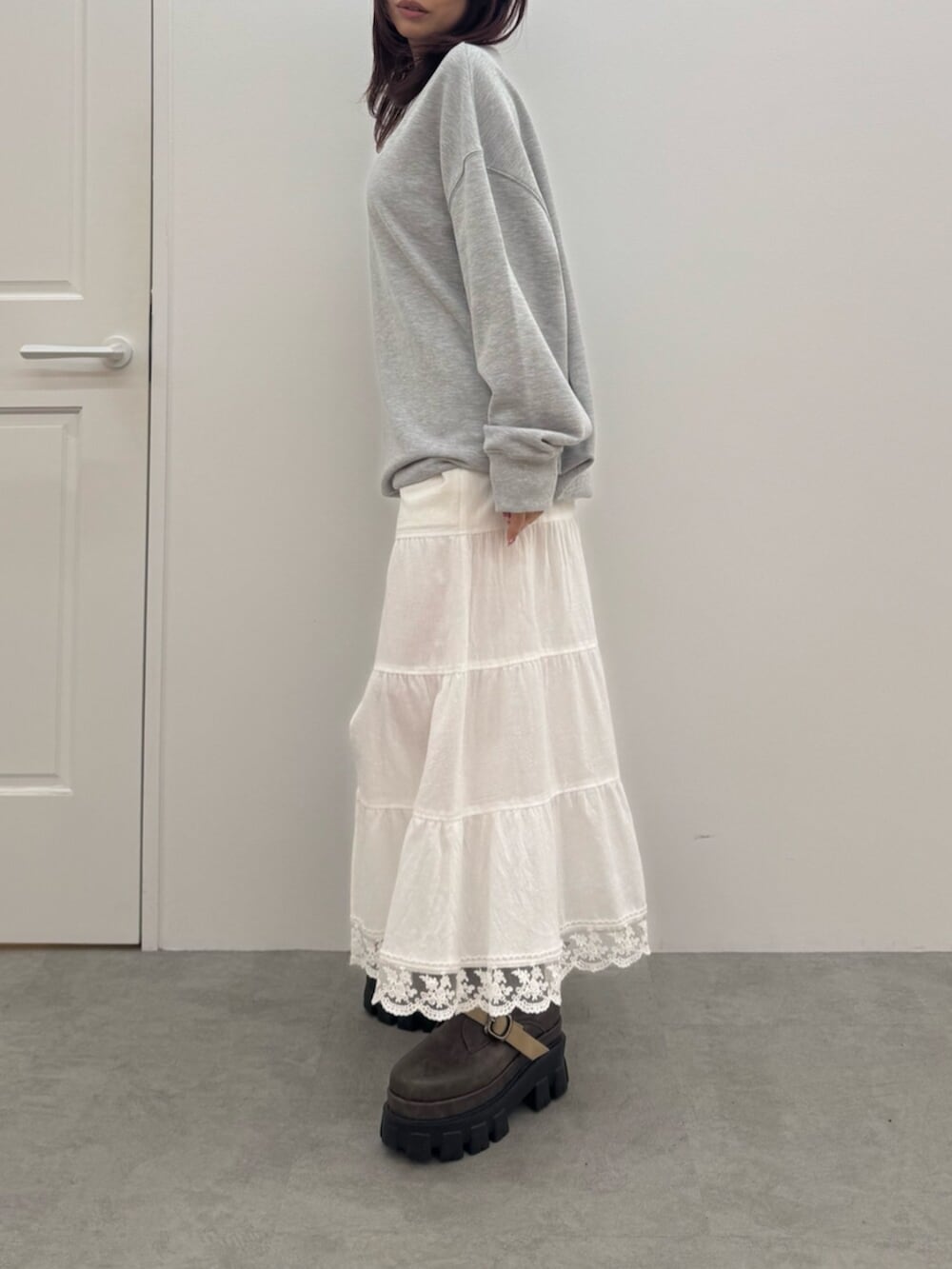 ブラウン系のブーツ、グレー系のスウェット、ホワイト系のスカートを着用したレディースの冬コーディネートの2枚目の写真