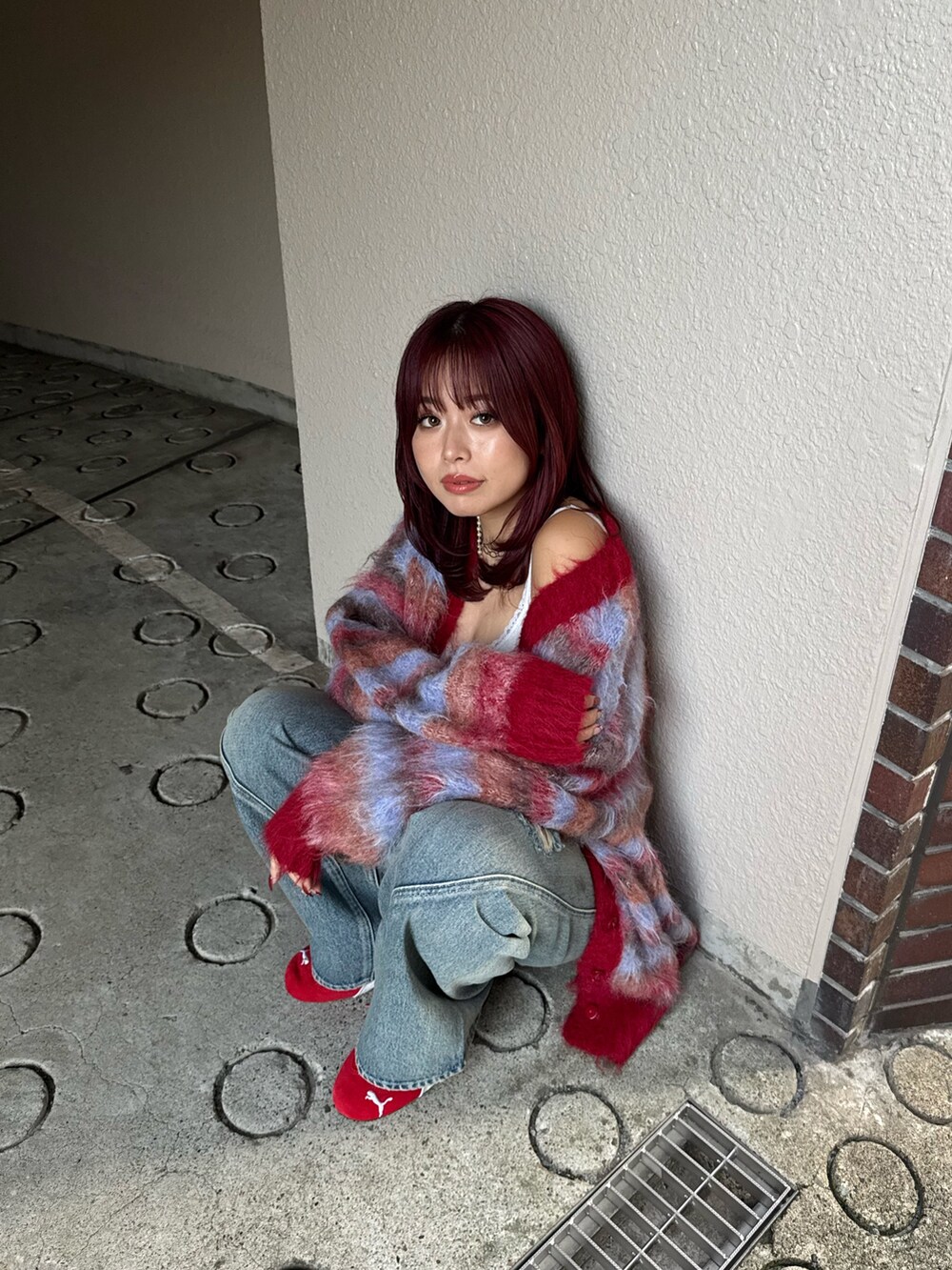 レッド系のカーディガン/ボレロ、ブルー系のデニムパンツ、レッド系のスニーカーを着用したレディースの冬コーディネートの5枚目の写真