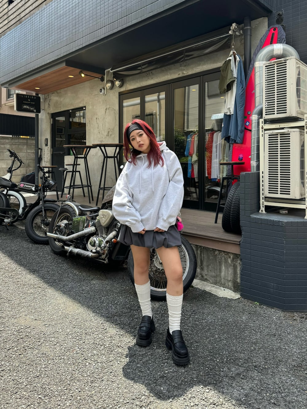 グレー系のパーカー、グレー系のスカート、ブラック系のローファーを着用したレディースの夏コーディネートの2枚目の写真