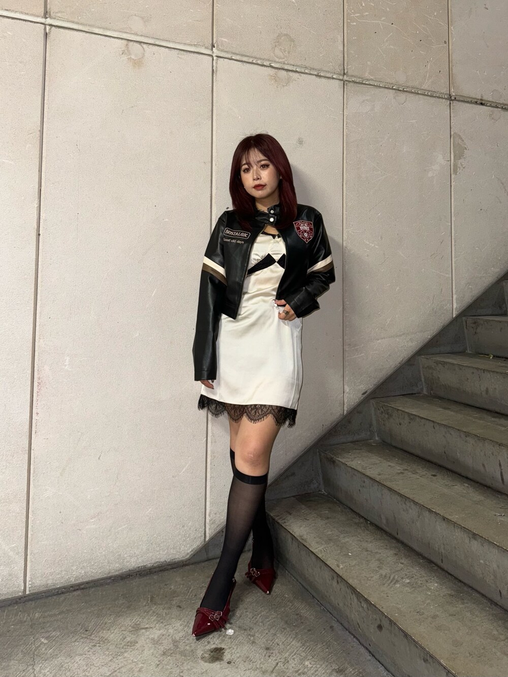 ブラック系のライダースジャケット、ホワイト系のワンピースを着用したレディースの秋コーディネートの2枚目の写真