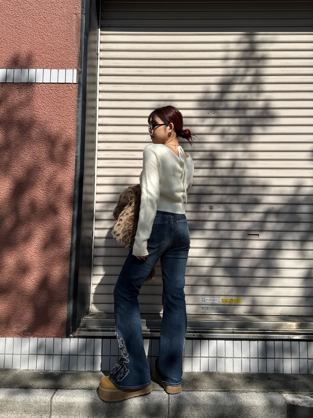 ホワイト系のニット/セーター、ブルー系のデニムパンツ、ベージュ系のスリッポンを着用したレディースの秋コーディネートの3枚目の写真