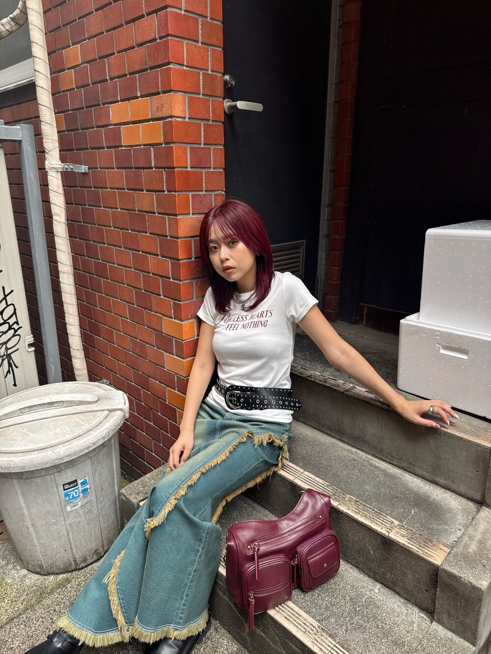 ブルー系のデニムスカート、ブラック系のブーツ、レッド系のハンドバッグを着用したレディースの夏コーディネートの3枚目の写真