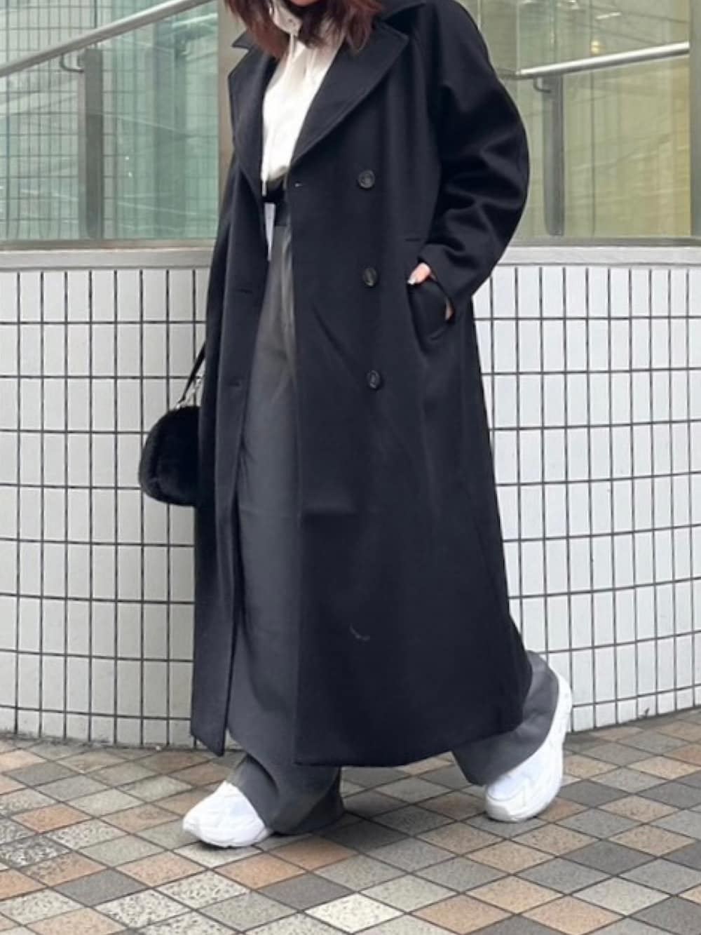 ブラック系のチェスターコート、ホワイト系のパーカー、グレー系のその他パンツを着用したレディースの冬コーディネートの4枚目の写真