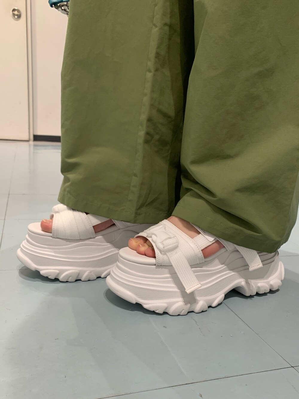 グレー系のタンクトップ、グリーン系のカーゴパンツ、ホワイト系のショルダーバッグを着用したレディースの春コーディネートの6枚目の写真