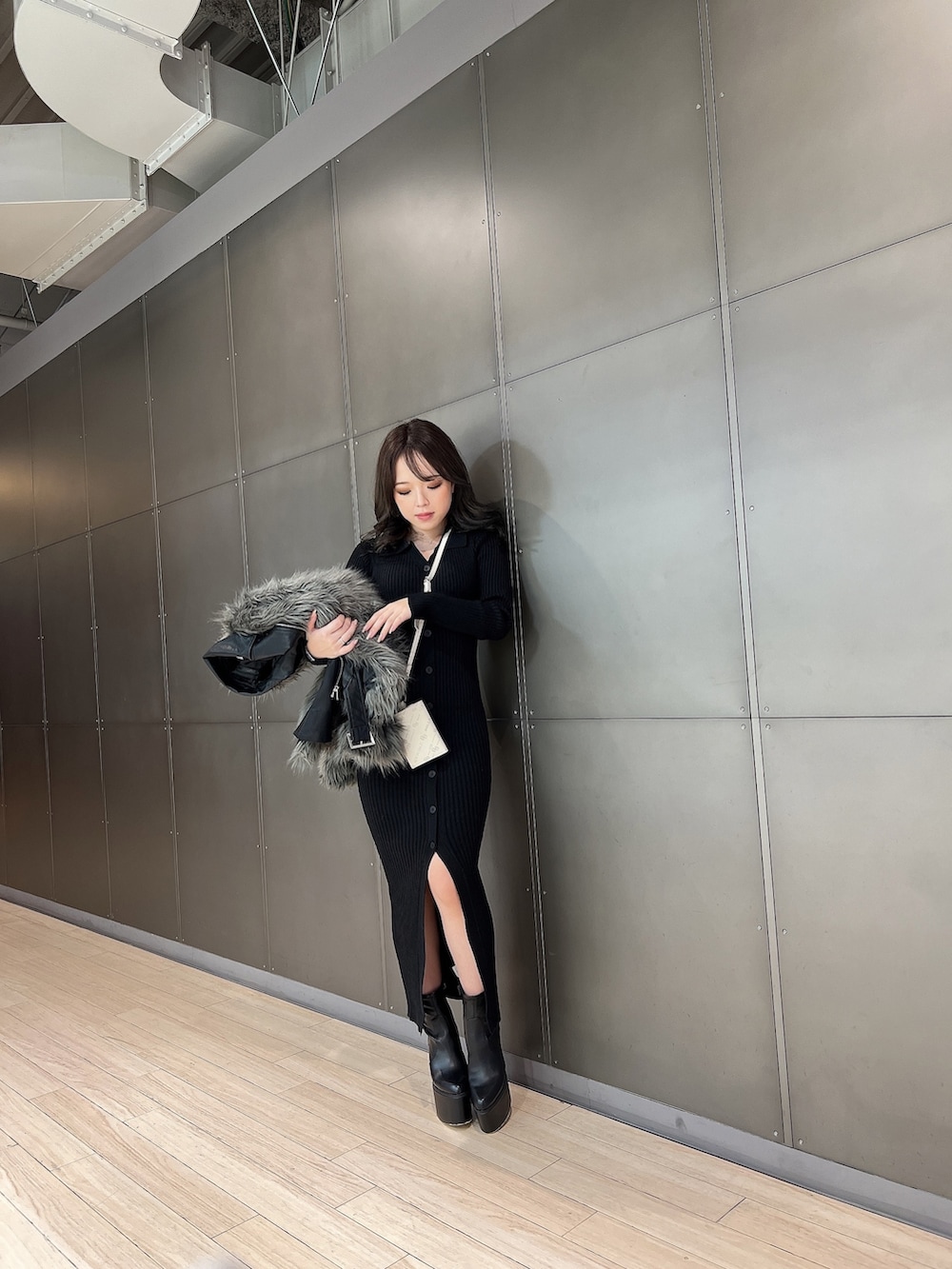 グレー系のライダースジャケット、ブラック系のワンピース、ブラック系のブーツを着用したレディースの冬コーディネートの3枚目の写真