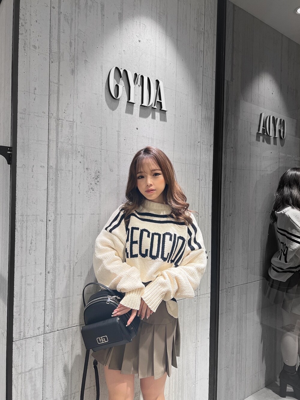 ベージュ系のスカート、ホワイト系のニット/セーター、ブラック系のブーツを着用したレディースの冬コーディネートの3枚目の写真