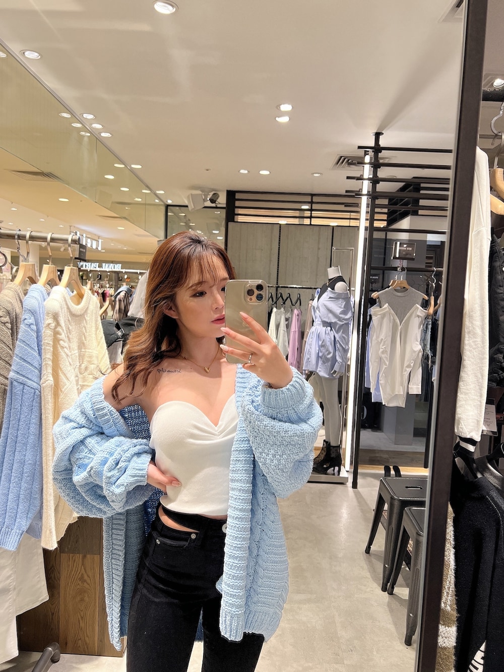 ブルー系のカーディガン/ボレロ、ホワイト系のチューブトップ、ブラック系のデニムパンツを着用したレディースの春コーディネートの4枚目の写真