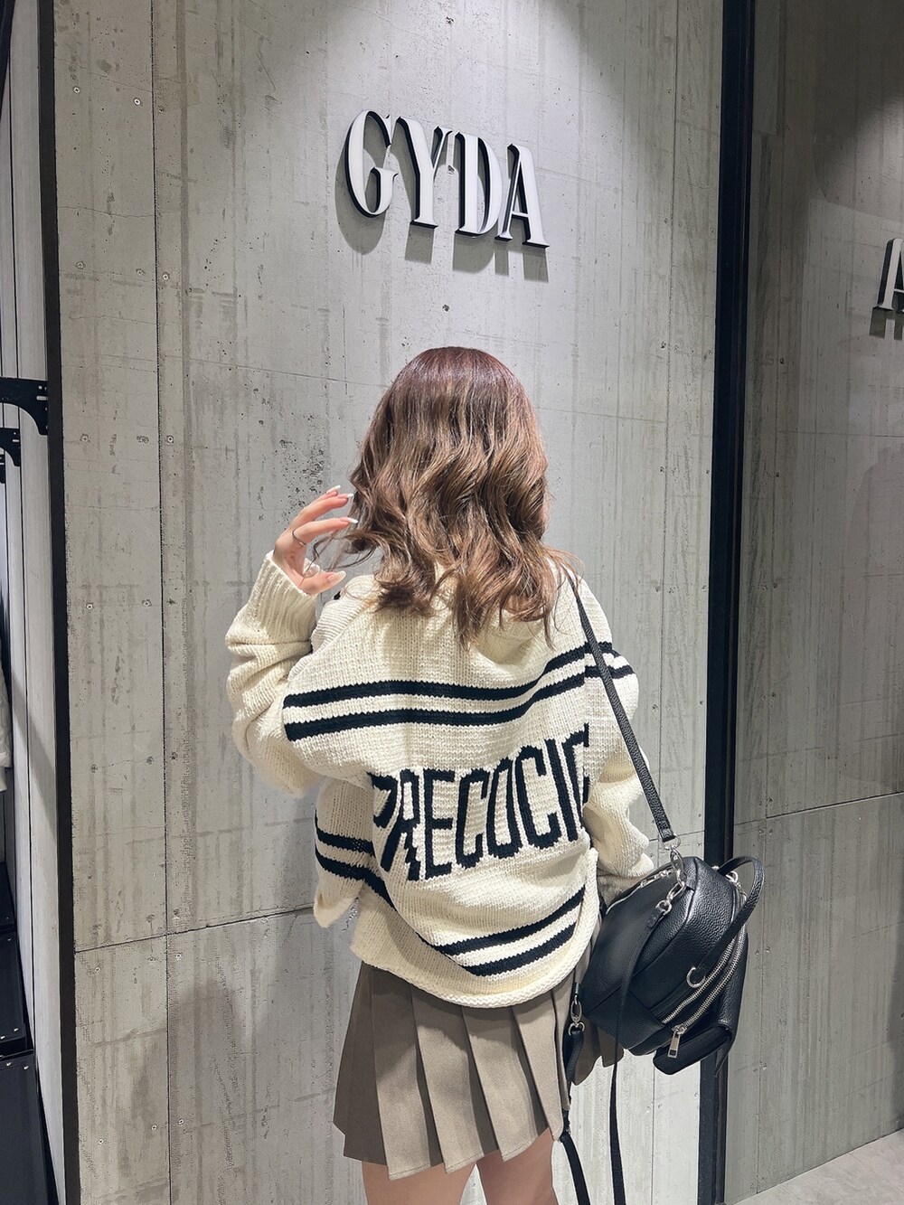 ベージュ系のスカート、ホワイト系のニット/セーター、ブラック系のブーツを着用したレディースの冬コーディネートの4枚目の写真