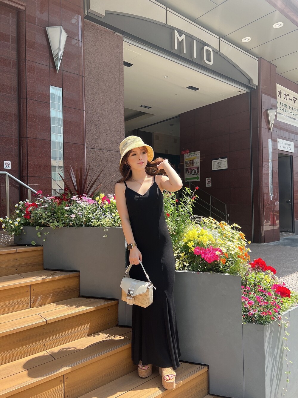 ブラック系のワンピース、ホワイト系のサンダル、ホワイト系のハンドバッグを着用したレディースの春コーディネートの3枚目の写真