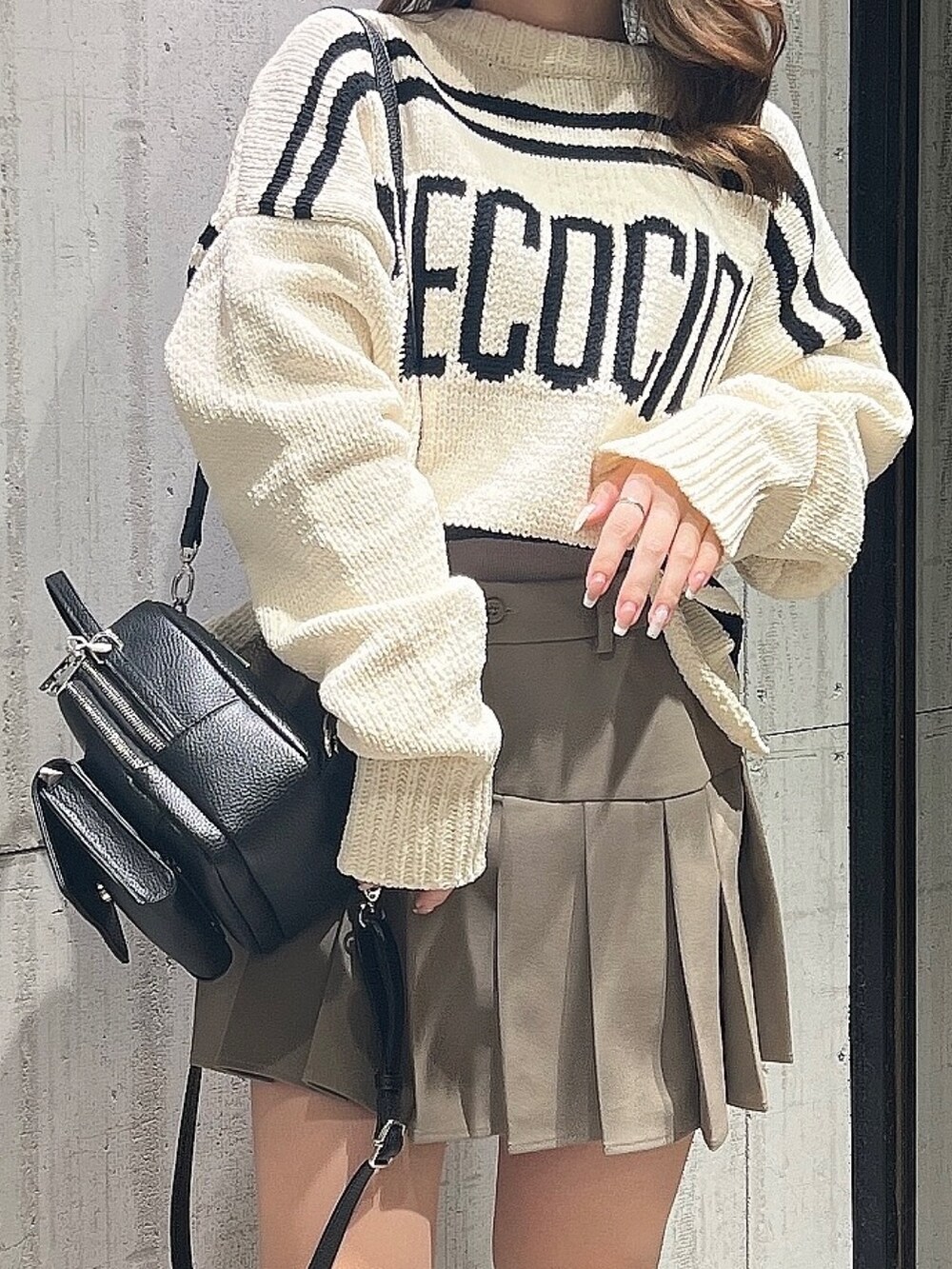 ベージュ系のスカート、ホワイト系のニット/セーター、ブラック系のブーツを着用したレディースの冬コーディネートの6枚目の写真