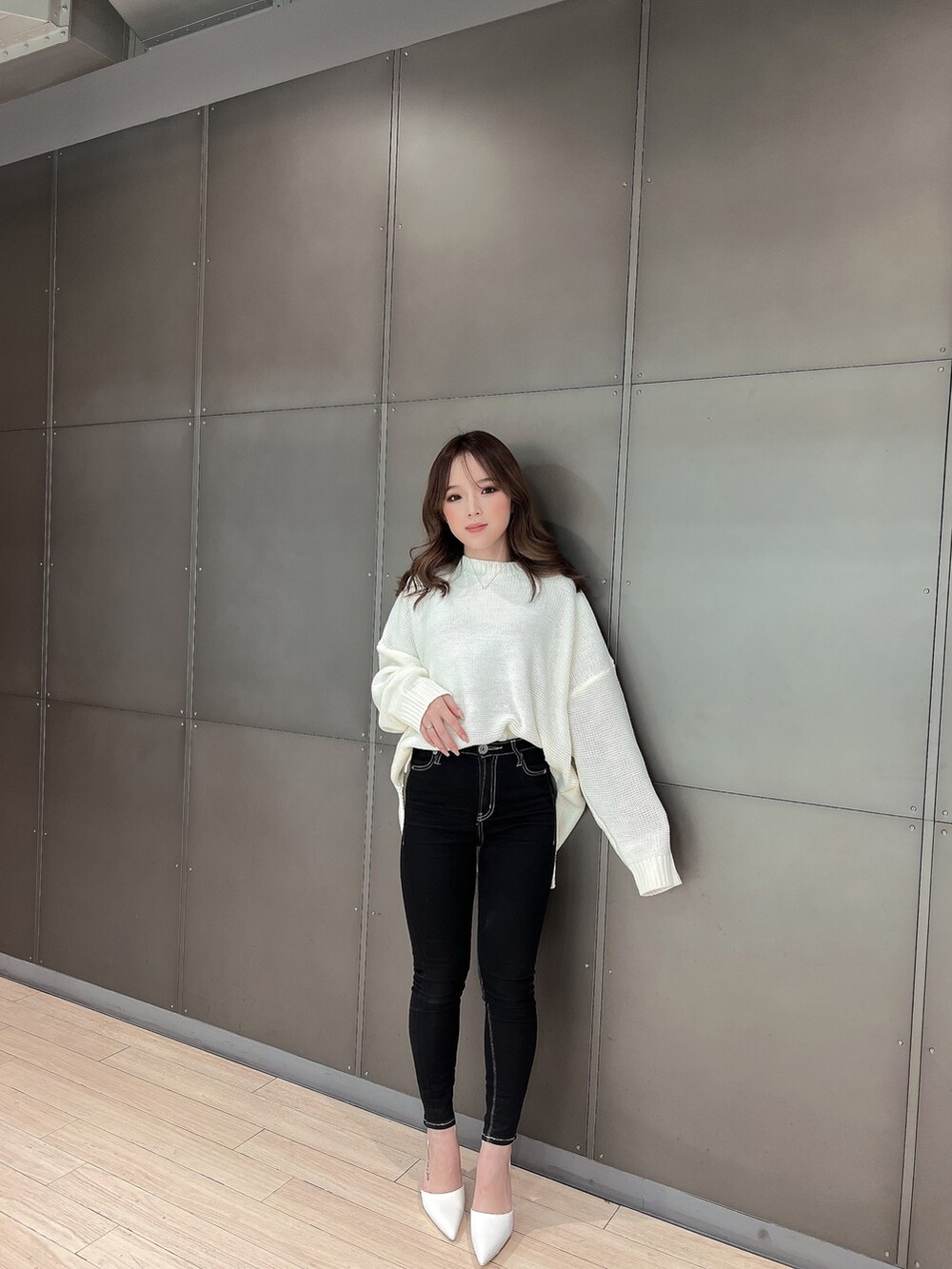 ホワイト系のニット/セーター、ブラック系のデニムパンツ、ホワイト系のパンプスを着用したレディースの冬コーディネートの5枚目の写真