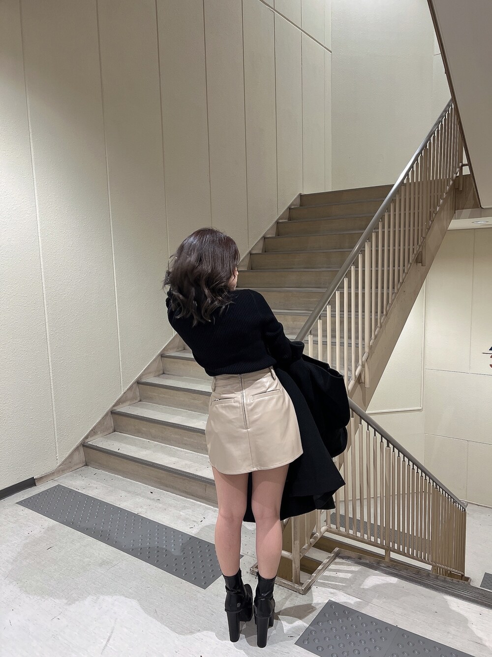 ブラック系のニット/セーター、ブラック系のトレンチコート、ブラック系のブーツを着用したレディースの冬コーディネートの7枚目の写真