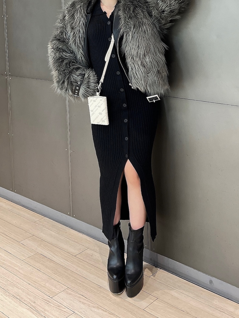 グレー系のライダースジャケット、ブラック系のワンピース、ブラック系のブーツを着用したレディースの冬コーディネートの6枚目の写真