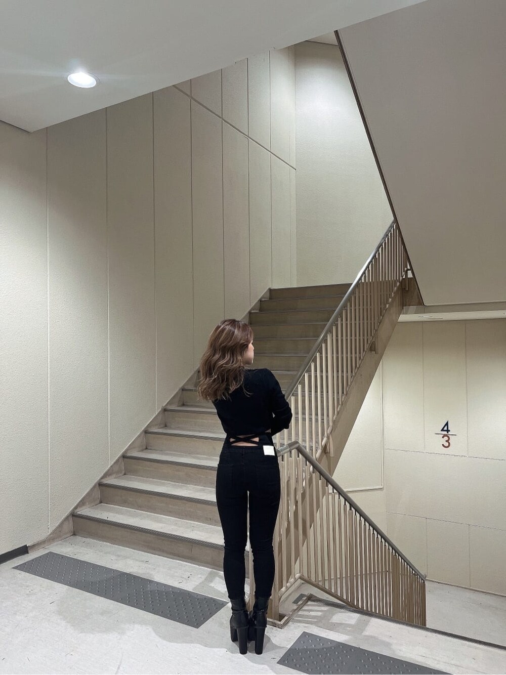 ブラック系のデニムパンツ、ブラック系のブーツ、ブラック系のニット/セーターを着用したレディースの秋コーディネートの4枚目の写真