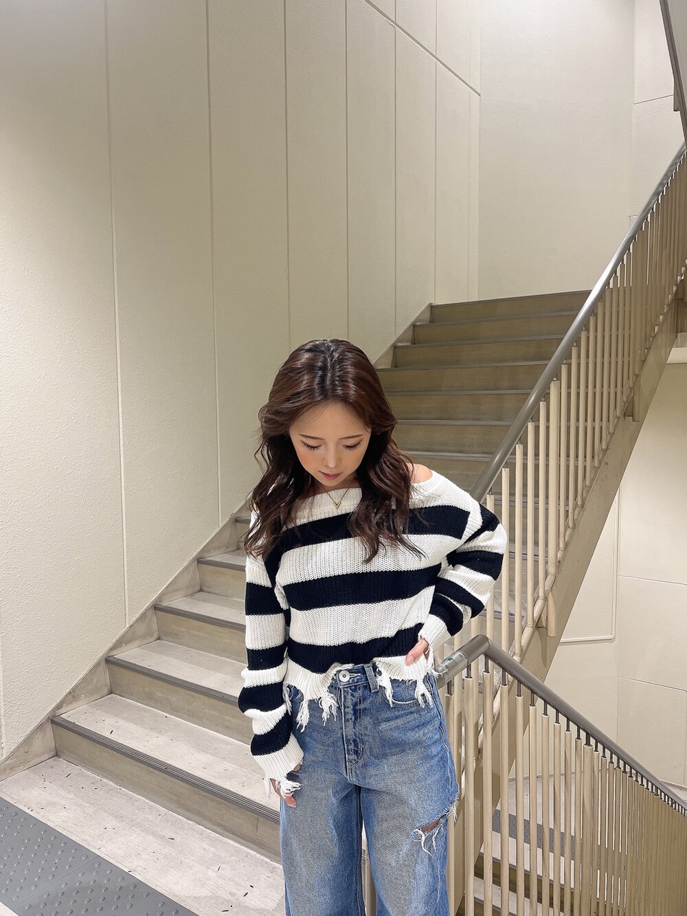 ブルー系のデニムパンツ、ブラック系のニット/セーター、ホワイト系のサンダルを着用したレディースの夏コーディネートの5枚目の写真