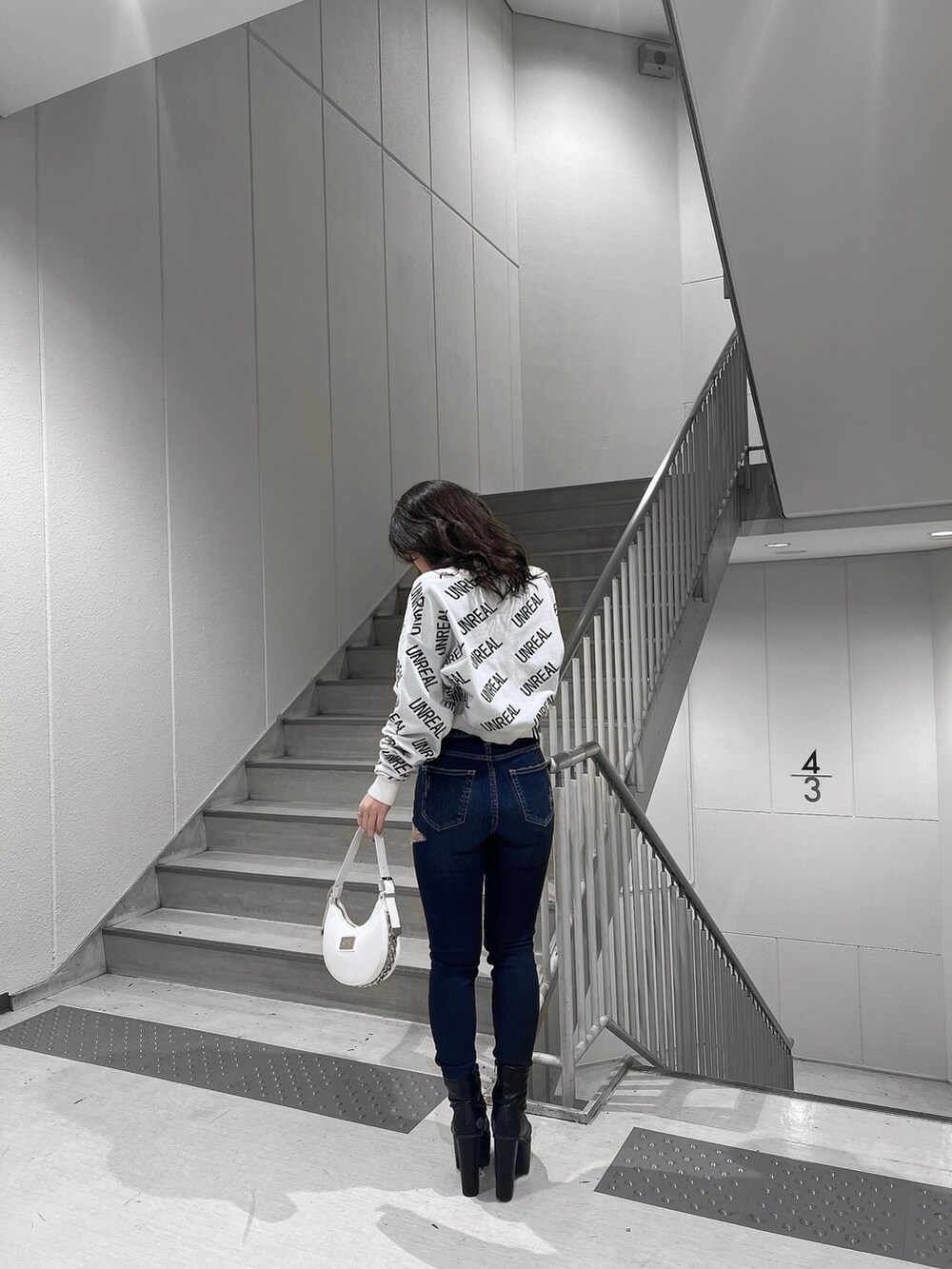 ホワイト系のニット/セーター、ブルー系のデニムパンツ、ホワイト系のハンドバッグを着用したレディースの冬コーディネートの2枚目の写真