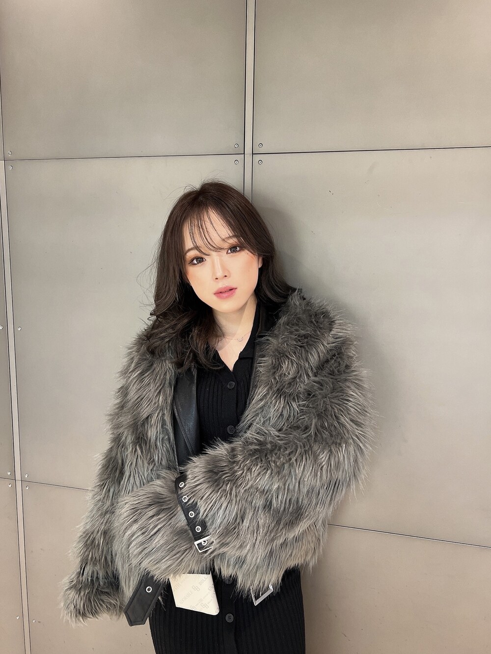 グレー系のライダースジャケット、ブラック系のワンピース、ブラック系のブーツを着用したレディースの冬コーディネートの2枚目の写真