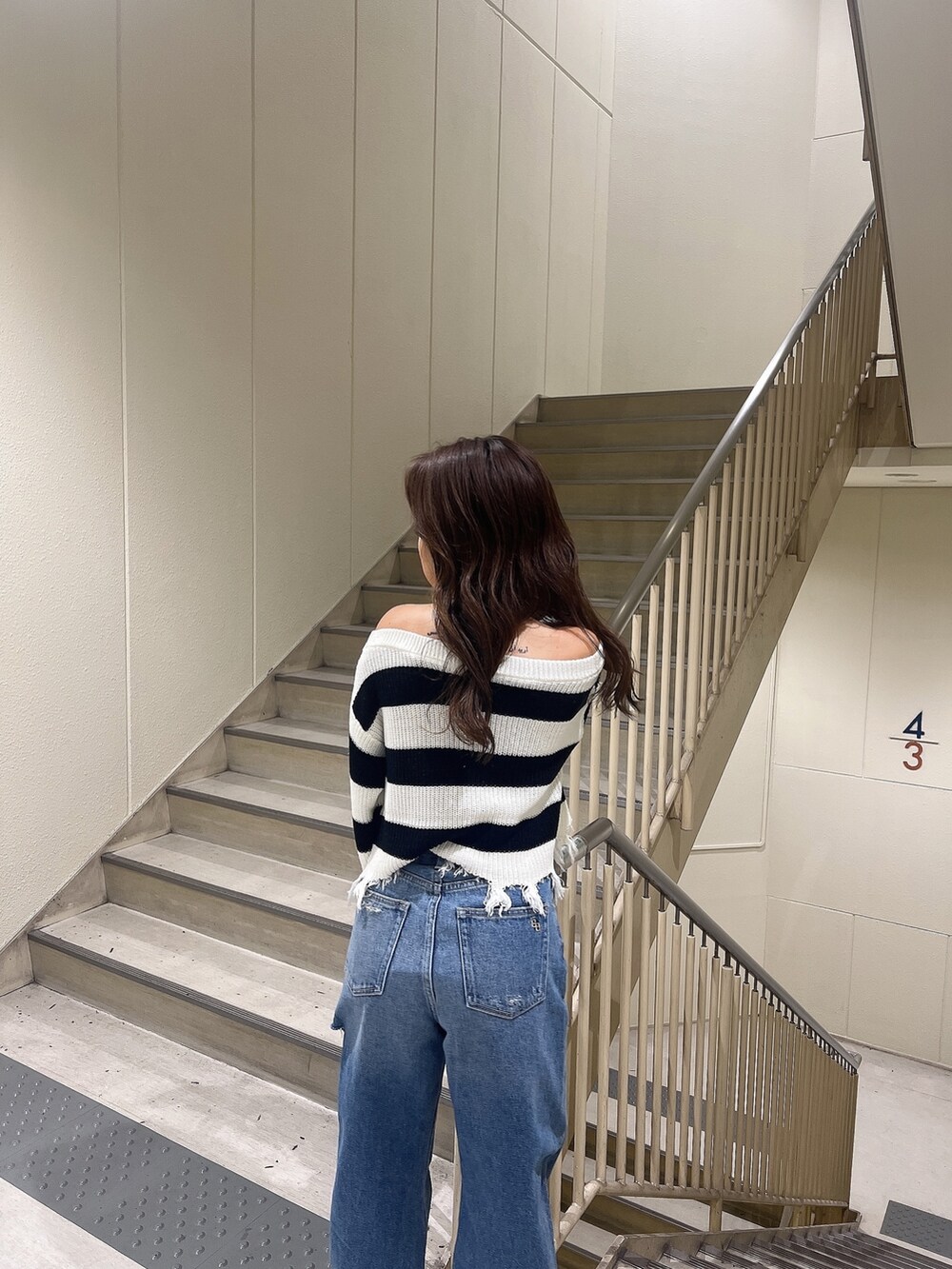 ブルー系のデニムパンツ、ブラック系のニット/セーター、ホワイト系のサンダルを着用したレディースの夏コーディネートの6枚目の写真