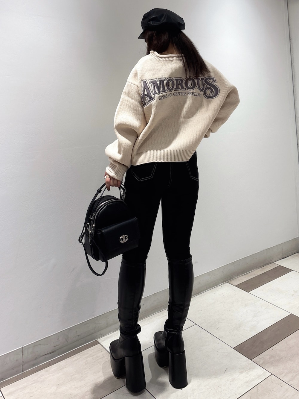 ピンク系のニット/セーター、ブラック系のブーツ、ブラック系のバックパック/リュックを着用したレディースの秋コーディネートの2枚目の写真