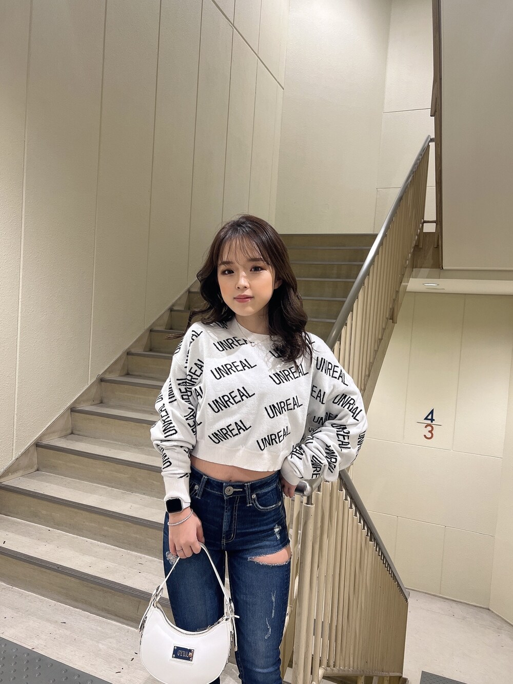 ホワイト系のニット/セーター、ブルー系のデニムパンツ、ホワイト系のハンドバッグを着用したレディースの冬コーディネートの4枚目の写真