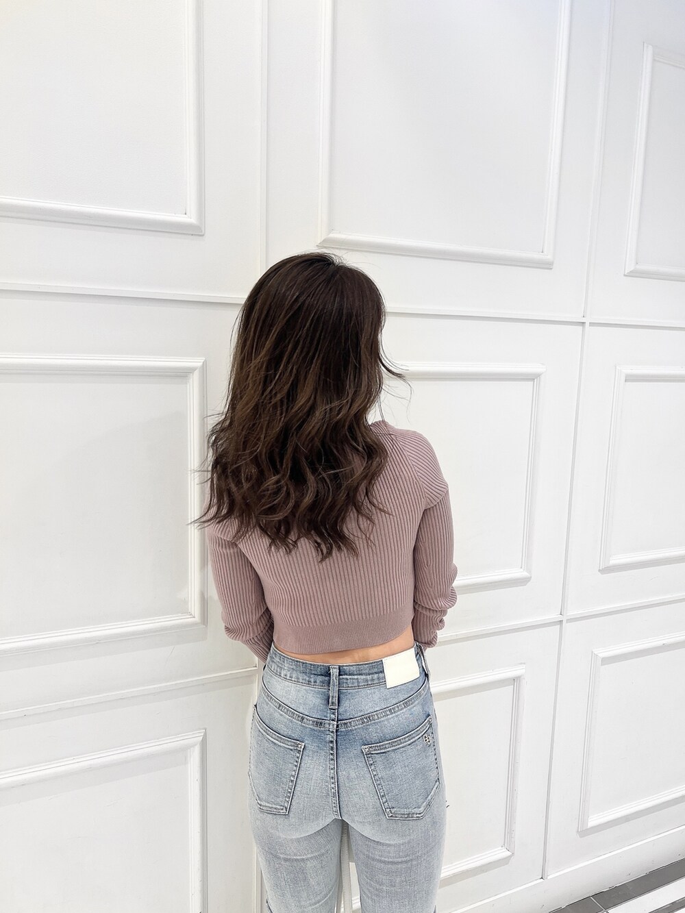 ピンク系のニット/セーター、ブルー系のデニムパンツ、ホワイト系のバックパック/リュックを着用したレディースの冬コーディネートの2枚目の写真