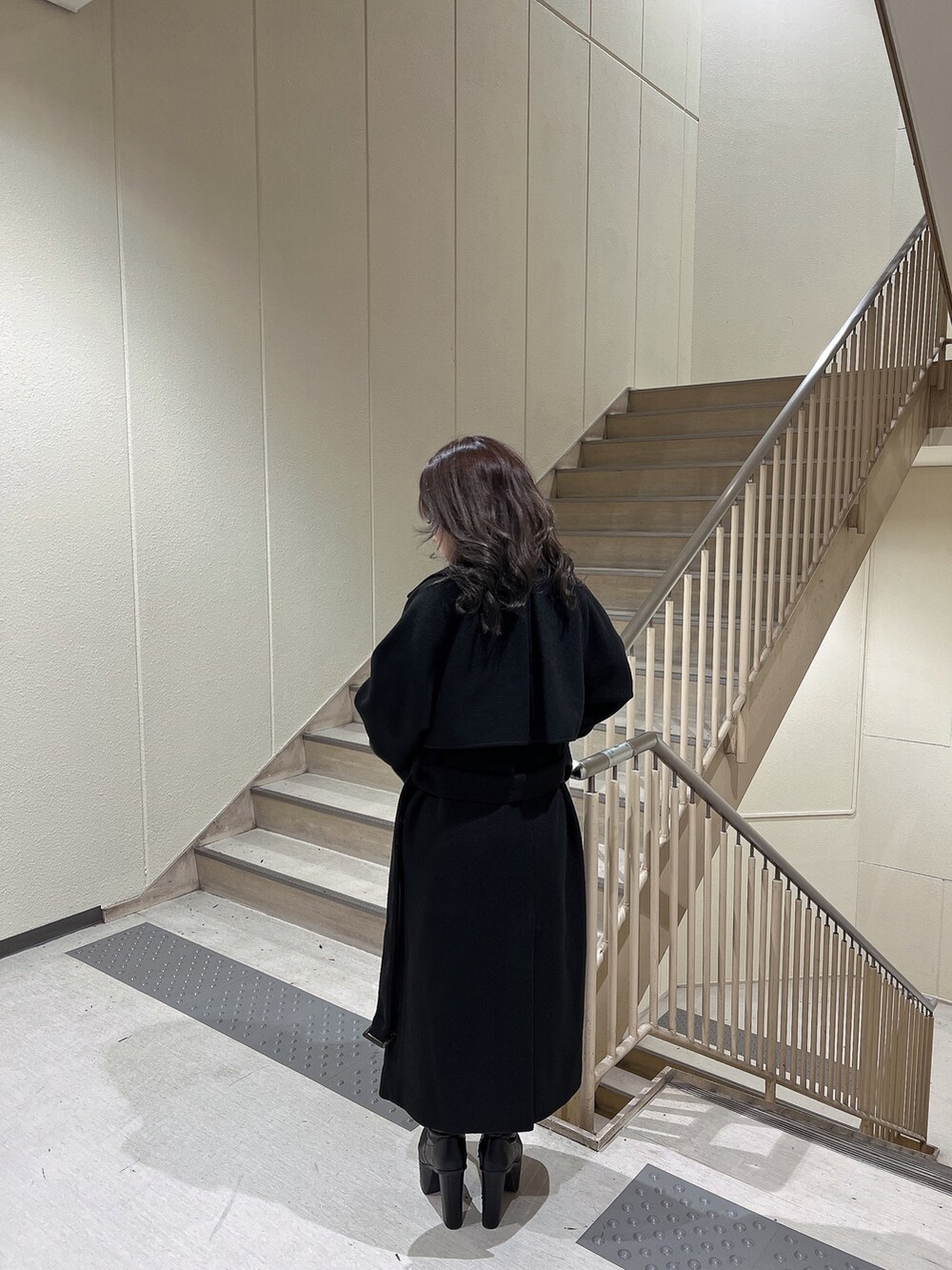 ブラック系のニット/セーター、ブラック系のトレンチコート、ブラック系のブーツを着用したレディースの冬コーディネートの3枚目の写真