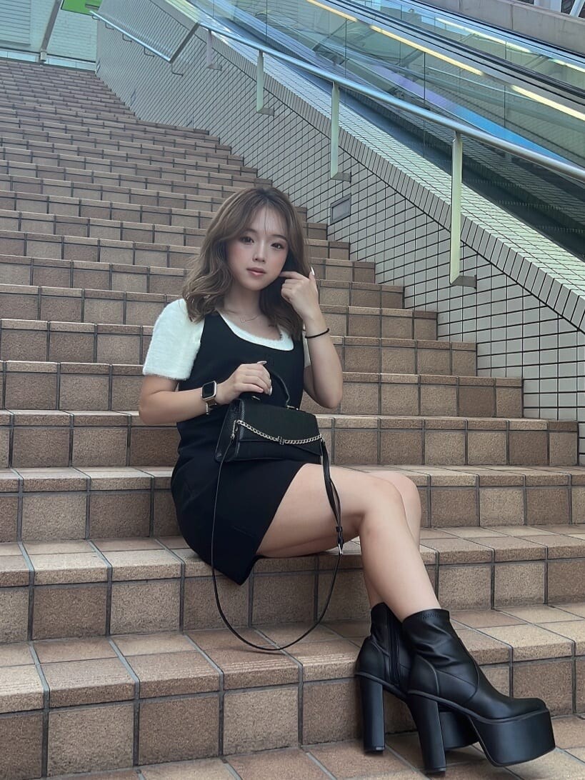 ホワイト系のニット/セーター、ブラック系のハンドバッグ、ブラック系のブーツを着用したレディースの夏コーディネートの3枚目の写真