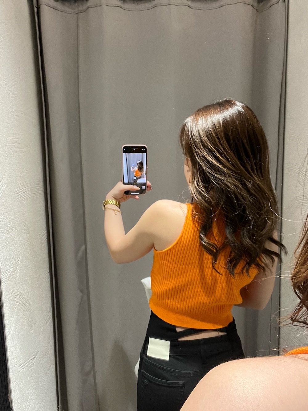 ホワイト系のサンダル、ブラック系のデニムパンツ、オレンジ系のニット/セーターを着用したレディースの春コーディネートの3枚目の写真