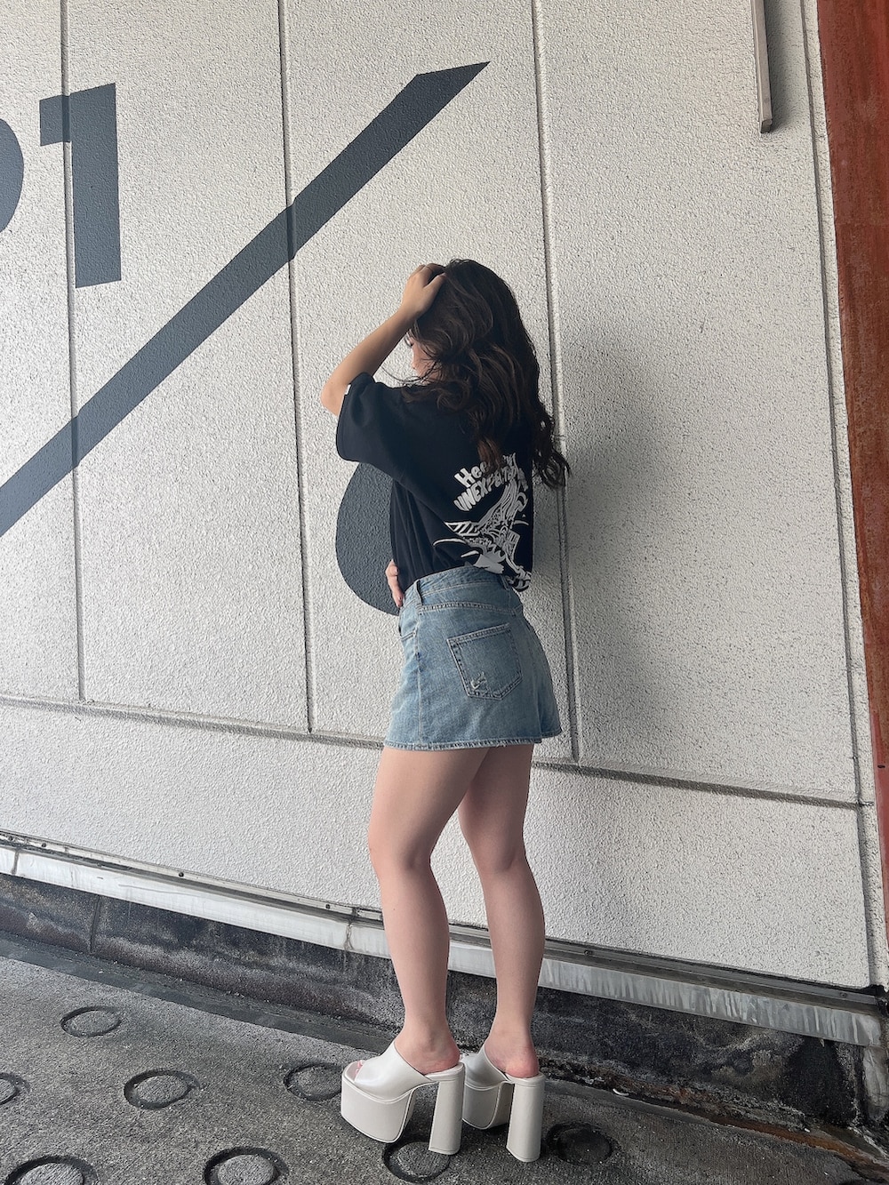 ブラック系のTシャツ/カットソー、ブルー系のデニムスカート、ホワイト系のサンダルを着用したレディースの夏コーディネートの3枚目の写真