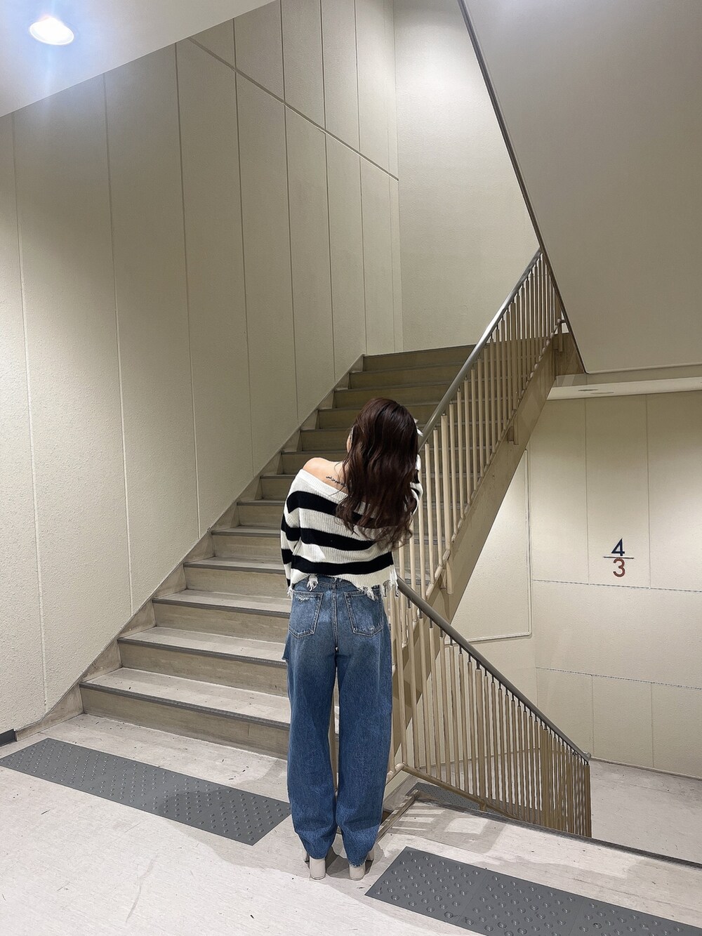 ブルー系のデニムパンツ、ブラック系のニット/セーター、ホワイト系のサンダルを着用したレディースの夏コーディネートの4枚目の写真