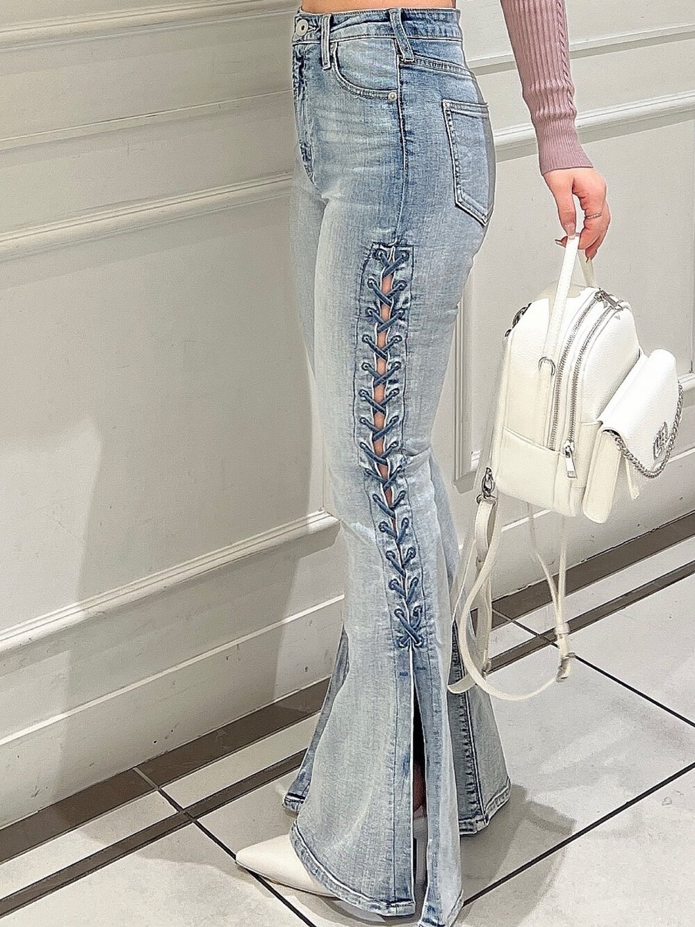 ピンク系のニット/セーター、ブルー系のデニムパンツ、ホワイト系のバックパック/リュックを着用したレディースの冬コーディネートの8枚目の写真