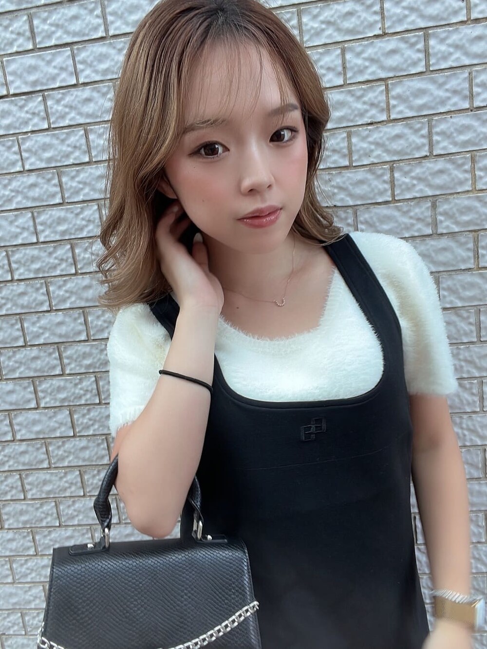 ホワイト系のニット/セーター、ブラック系のハンドバッグ、ブラック系のブーツを着用したレディースの夏コーディネートの4枚目の写真