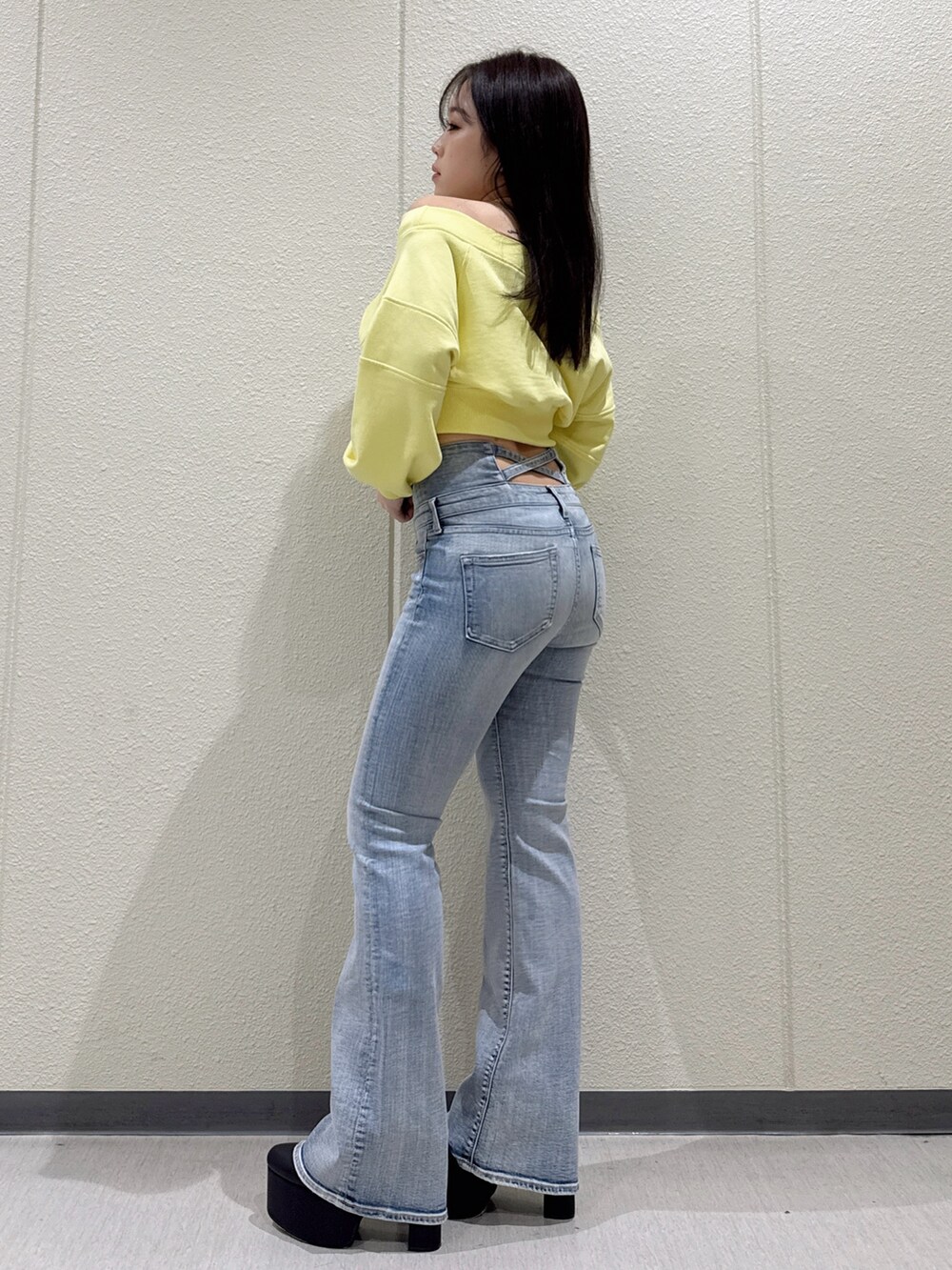 ブルー系のデニムパンツ、イエロー系のスウェット、ブラック系のブーツを着用したレディースの冬コーディネートの2枚目の写真