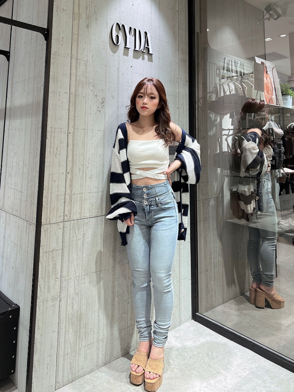 ブルー系のデニムパンツ、ブルー系のカーディガン/ボレロ、ホワイト系のキャミソールを着用したレディースの夏コーディネートの3枚目の写真