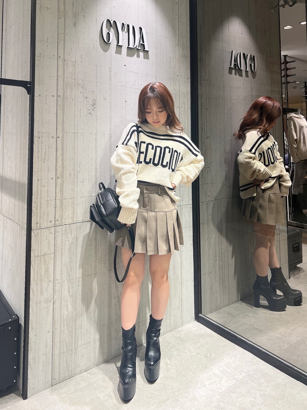 ベージュ系のスカート、ホワイト系のニット/セーター、ブラック系のブーツを着用したレディースの冬コーディネートの5枚目の写真