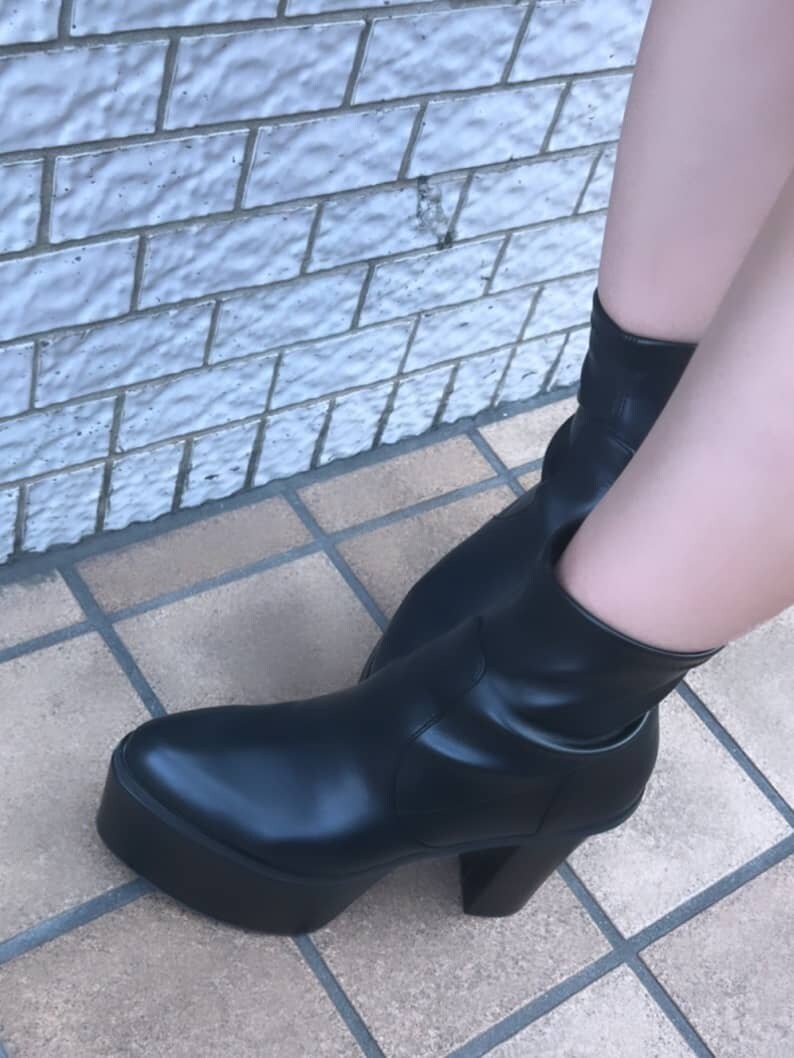 ホワイト系のニット/セーター、ブラック系のハンドバッグ、ブラック系のブーツを着用したレディースの夏コーディネートの6枚目の写真