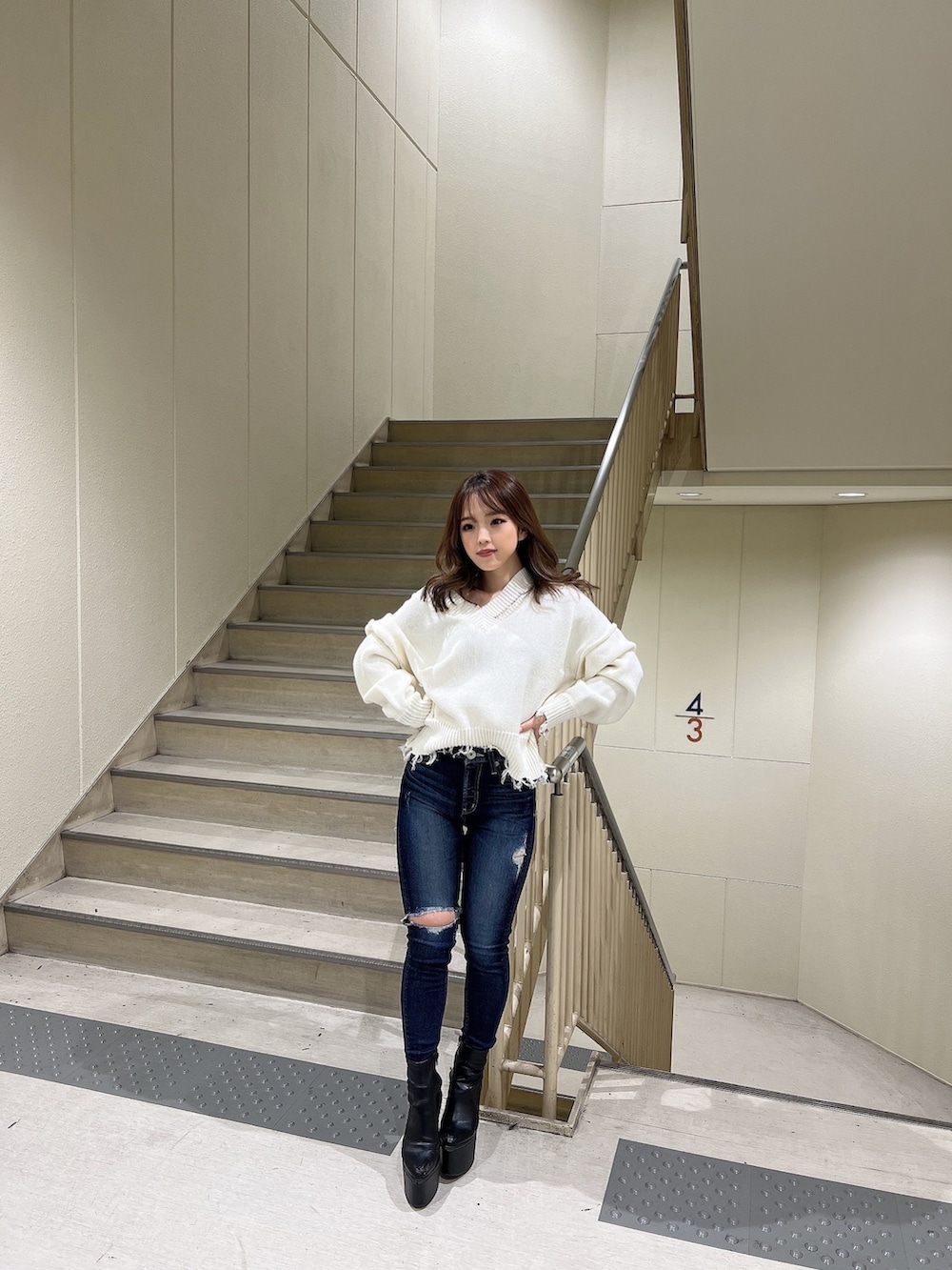 ブルー系のデニムパンツ、ホワイト系のニット/セーター、ブラック系のブーツを着用したレディースの冬コーディネートの2枚目の写真