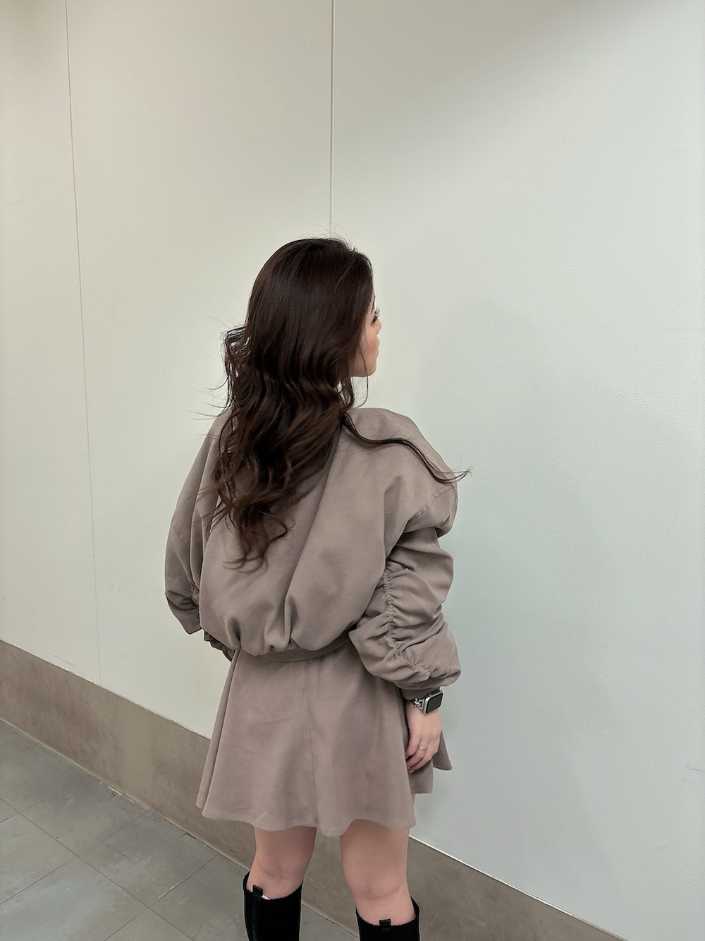 ブラック系のブーツ、ベージュ系のブルゾン、ベージュ系のスカートを着用したレディースの冬コーディネートの2枚目の写真