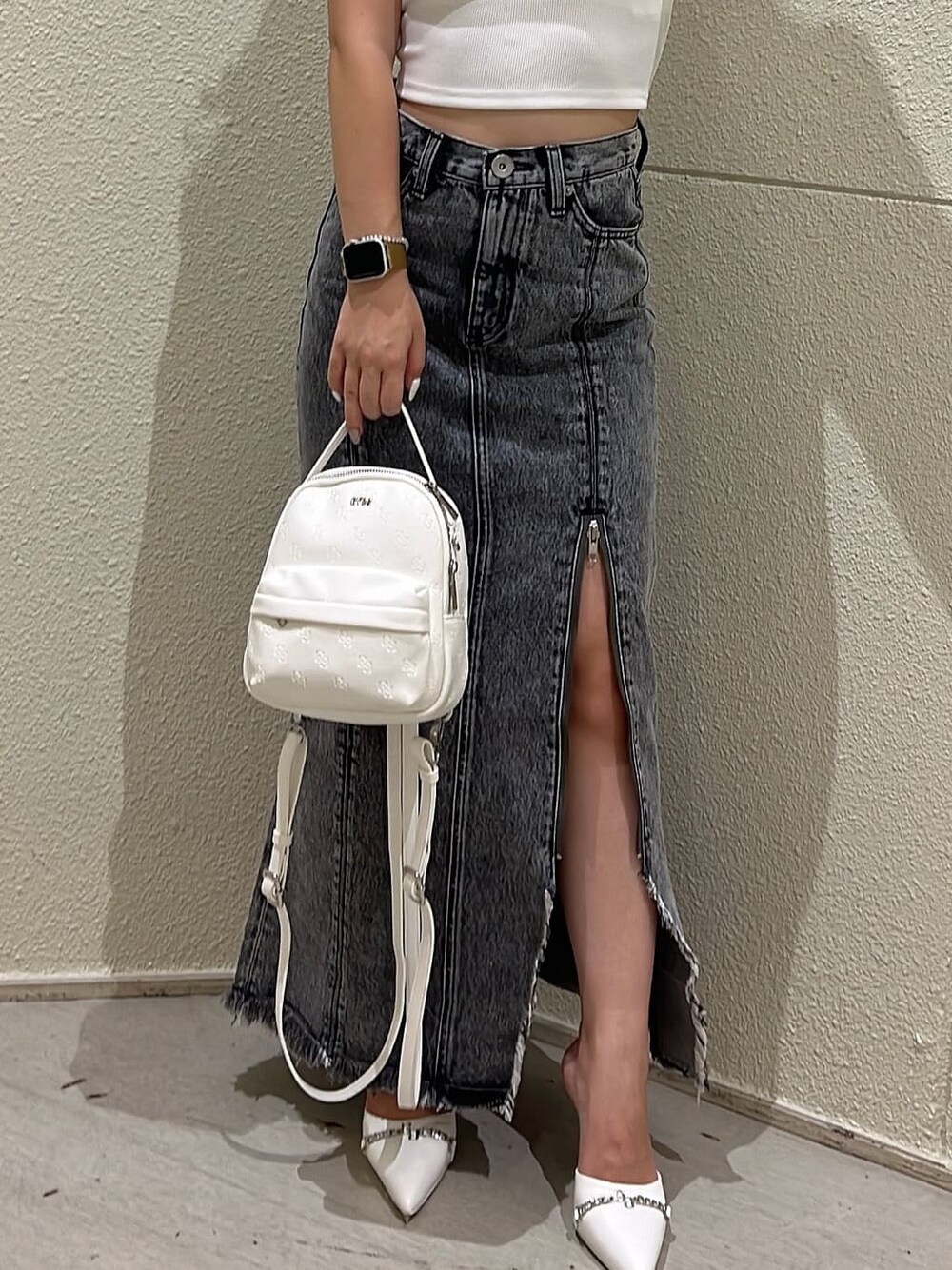 ホワイト系のバックパック/リュック、ブラック系のデニムスカート、ホワイト系のパンプスを着用したレディースの夏コーディネートの3枚目の写真