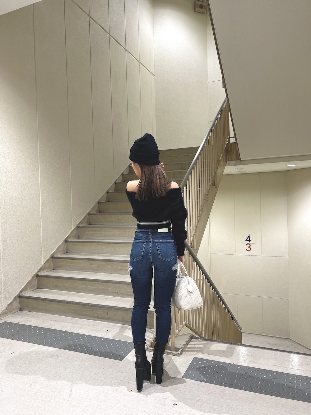 ブラック系のニット/セーター、ブルー系のデニムパンツ、ブラック系のブーツを着用したレディースの秋コーディネートの5枚目の写真