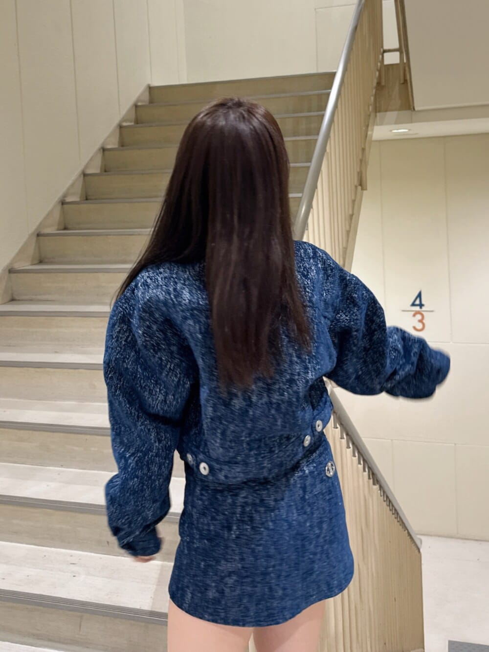 ブルー系のデニムジャケット、ブルー系のスカート、ホワイト系のキャミソールを着用したレディースの冬コーディネートの5枚目の写真