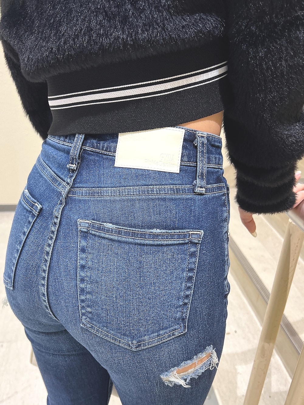 ブラック系のニット/セーター、ブルー系のデニムパンツ、ブラック系のブーツを着用したレディースの秋コーディネートの7枚目の写真