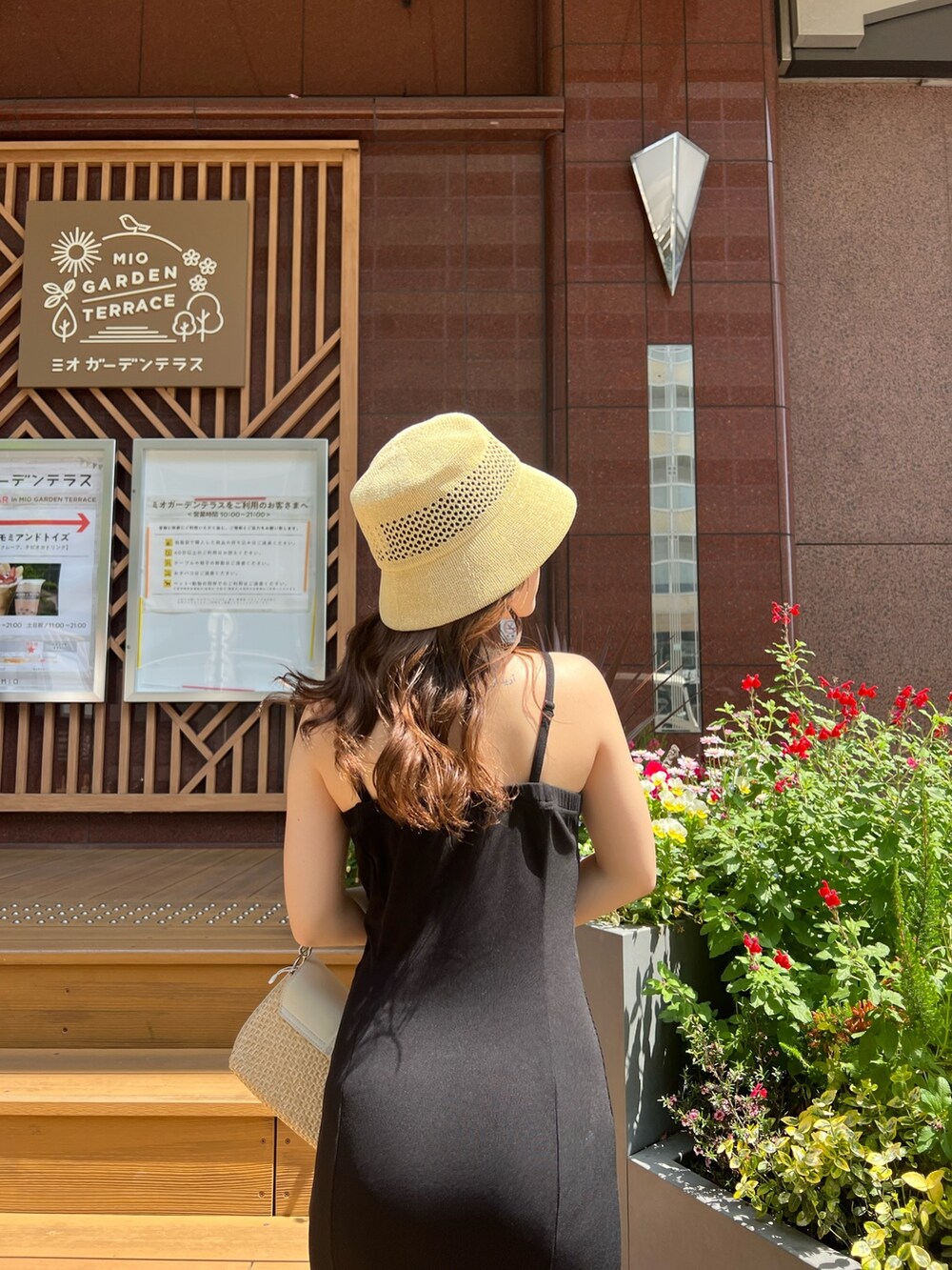 ブラック系のワンピース、ホワイト系のサンダル、ホワイト系のハンドバッグを着用したレディースの春コーディネートの4枚目の写真