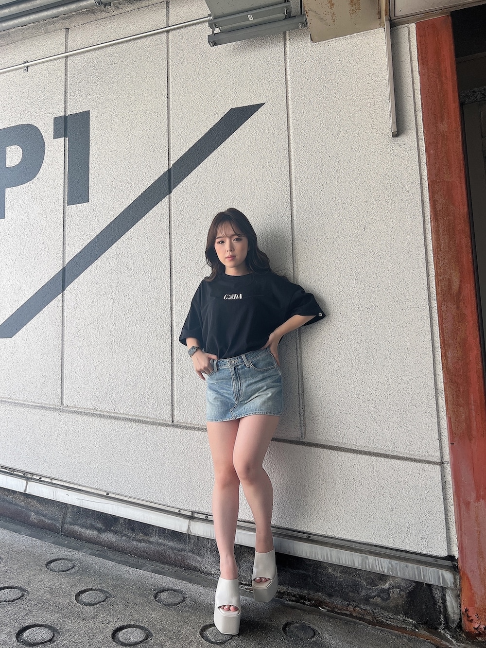 ブラック系のTシャツ/カットソー、ブルー系のデニムスカート、ホワイト系のサンダルを着用したレディースの夏コーディネートの2枚目の写真